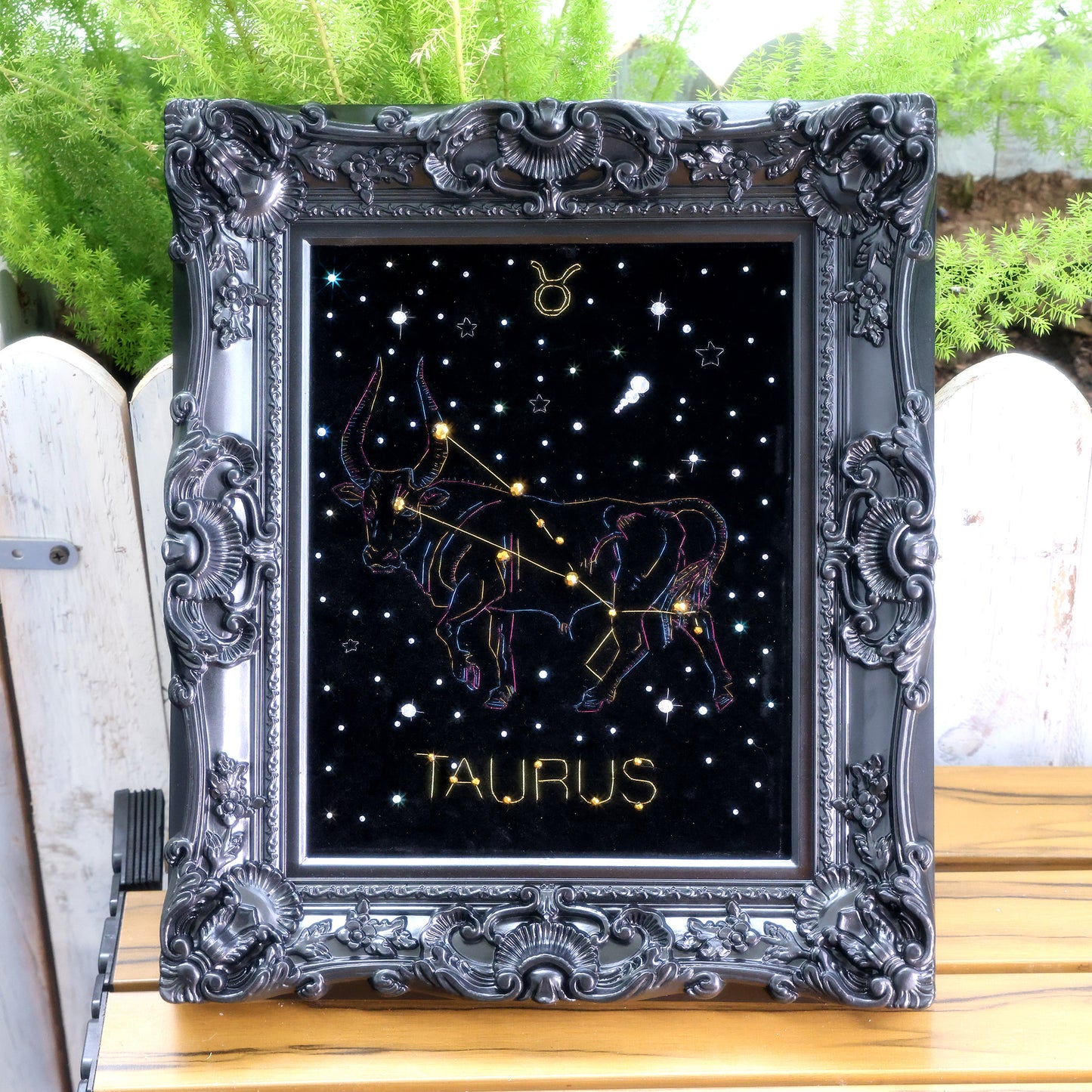 10 Inches  Hand-stitched Taurus constellation embroidery on black velvet with metallic thread and rhinestone accents, set in an ornate matte-black resin frame — ready to hang.