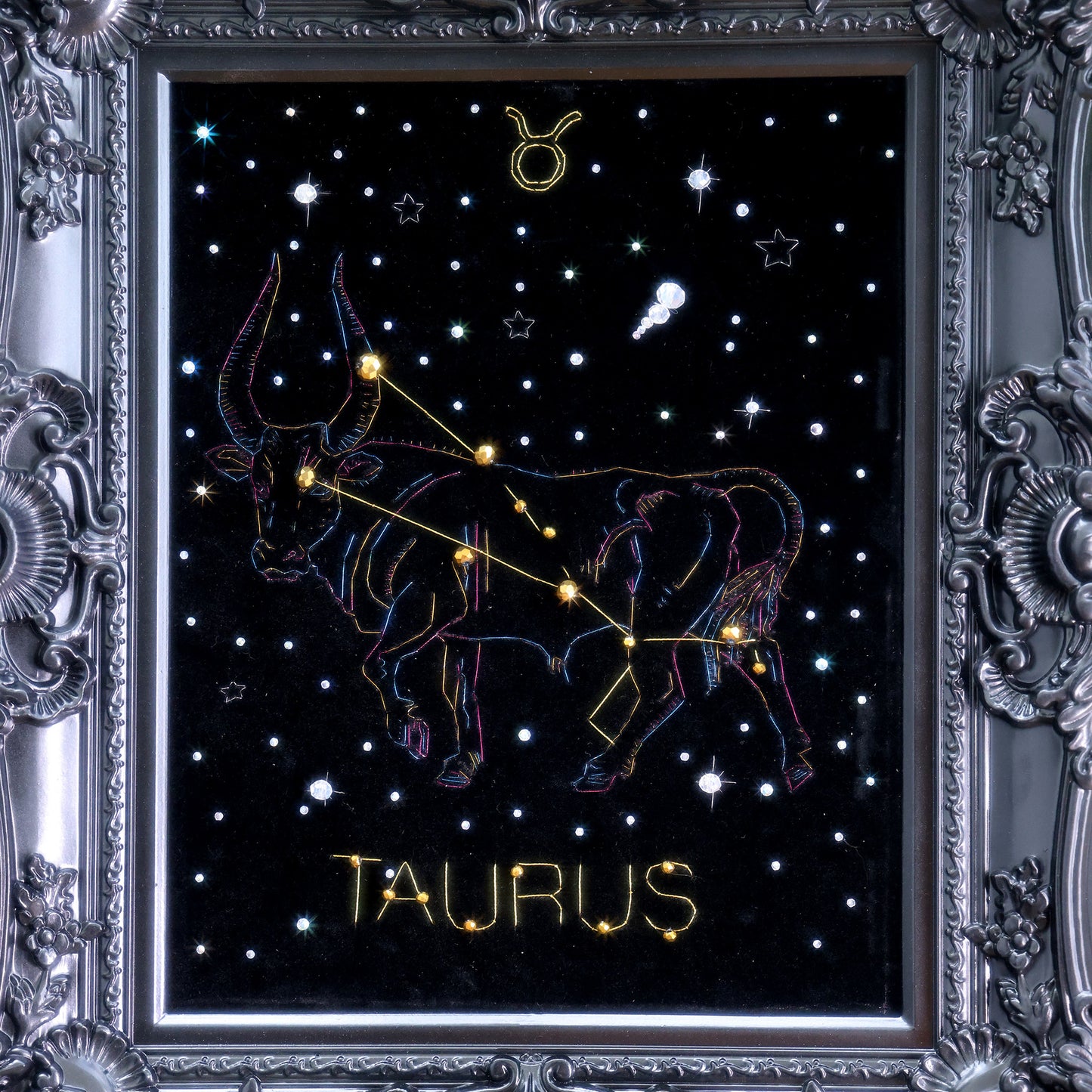 10 Inches  Hand-stitched Taurus constellation embroidery on black velvet with metallic thread and rhinestone accents, set in an ornate matte-black resin frame — ready to hang.