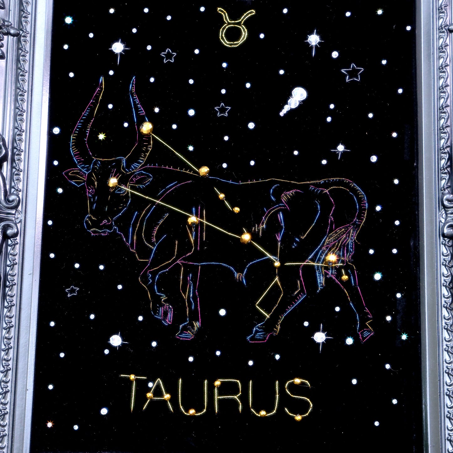 10 Inches  Hand-stitched Taurus constellation embroidery on black velvet with metallic thread and rhinestone accents, set in an ornate matte-black resin frame — ready to hang.