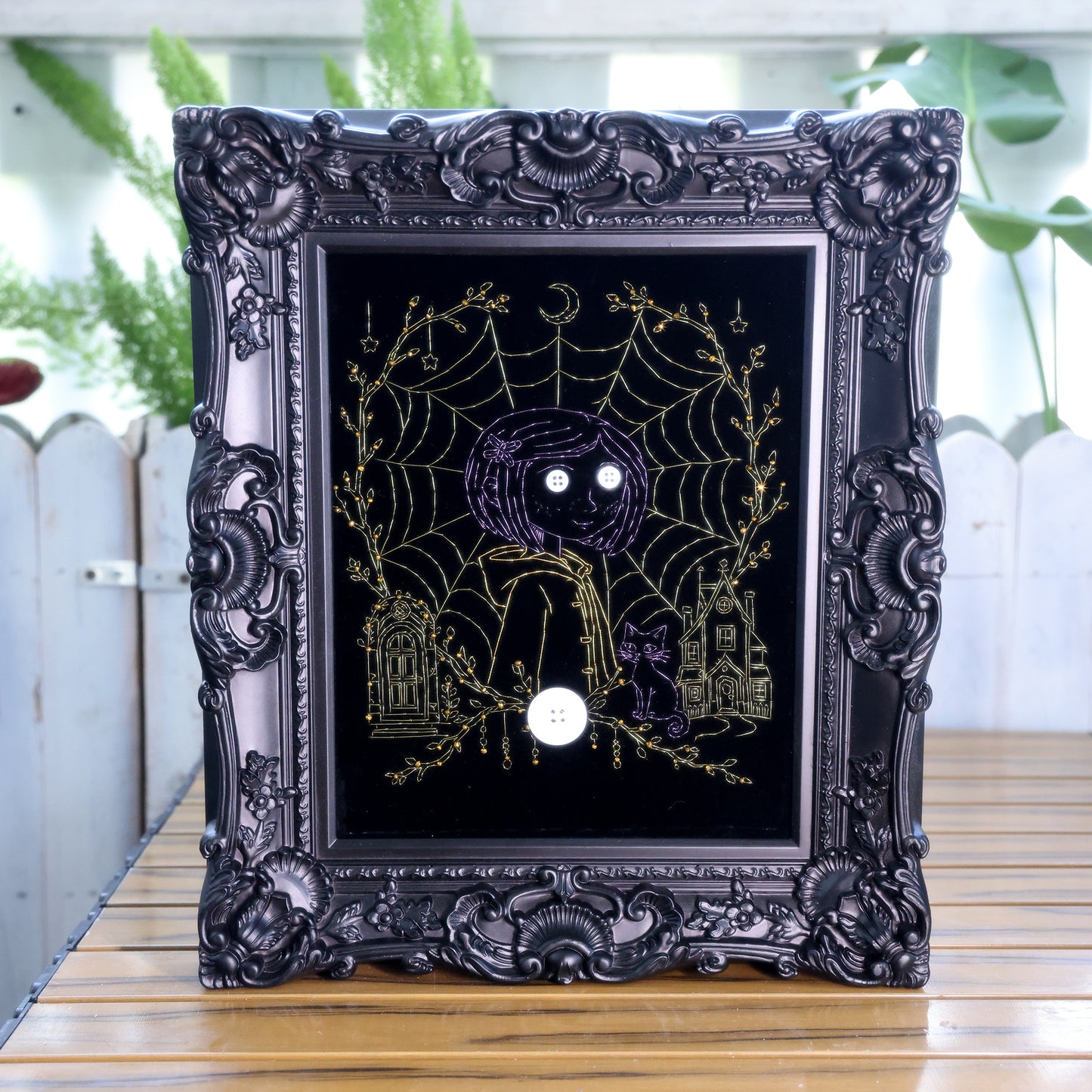 10 inches Original Coraline-themed embroidered wall art on black velvet with metallic thread, rhinestones, and button eyes in an ornate black frame. Handmade, ready to hang. Contains handmade embroidered decorative paintings.