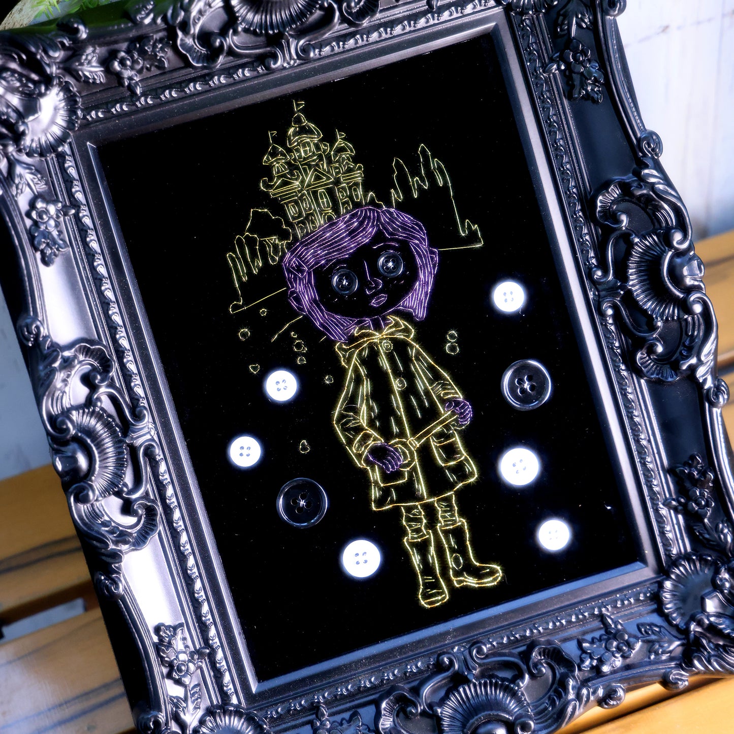 8 inches Handmade Coraline-inspired embroidered wall art on black velvet with metallic thread, buttons, and rhinestone accents in a matte ornate black frame — intentionally unglazed to showcase texture. Contains handmade embroidered decorative paintings.